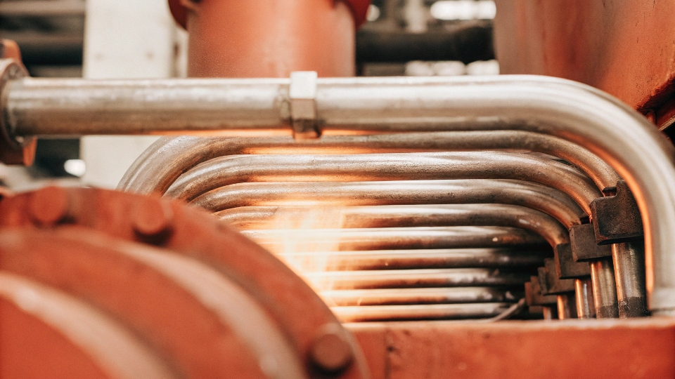 A close-up of a titanium U-bent tube installed within a large industrial heat exchanger