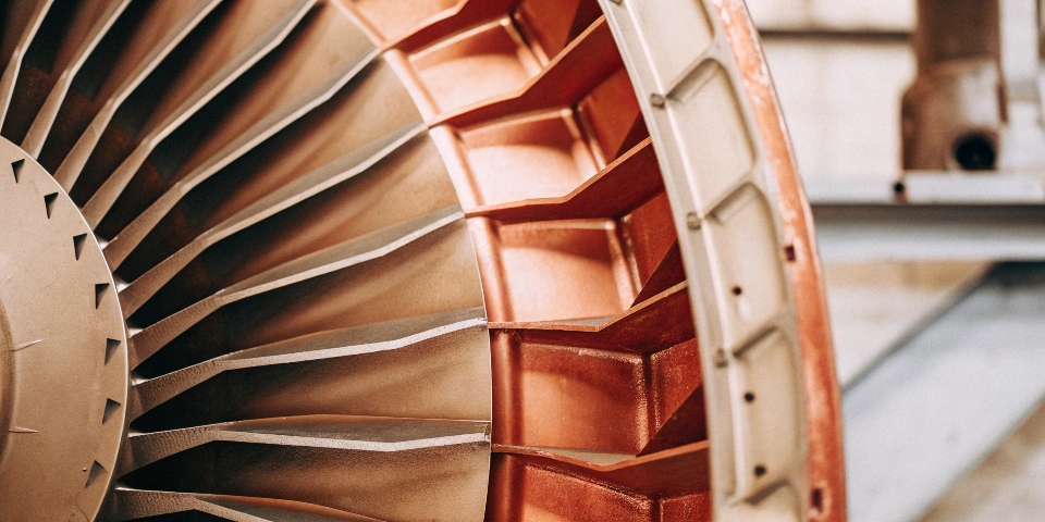 A close-up shot of a jet engine turbine blade and a structural airframe component made of titanium.