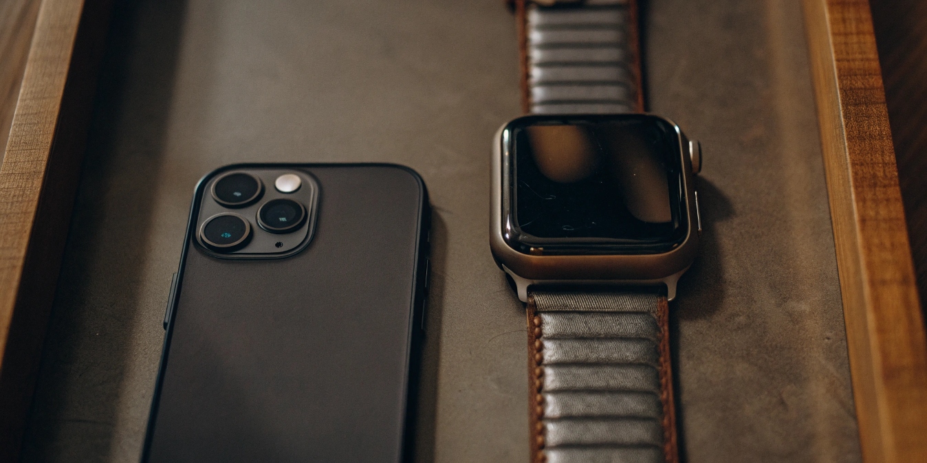 An iPhone 15 Pro next to an Apple Watch Ultra, both showing off their titanium frames.