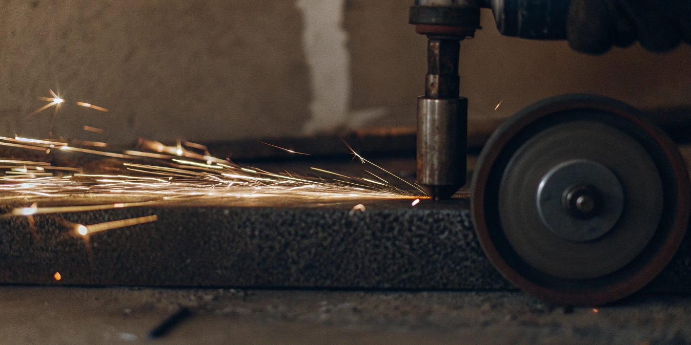 A close-up of a spark test on a piece of metal, showing brilliant white sparks
